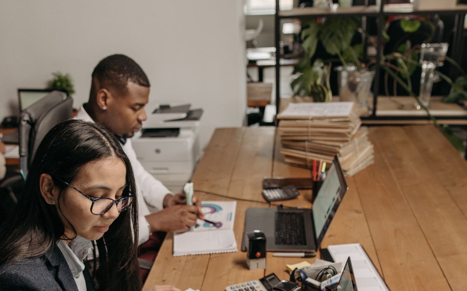 Deux comptables traitent des factures avec des ordinateurs portables dans un bureau moderne